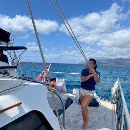 a person standing in front of a boat next to a body of water