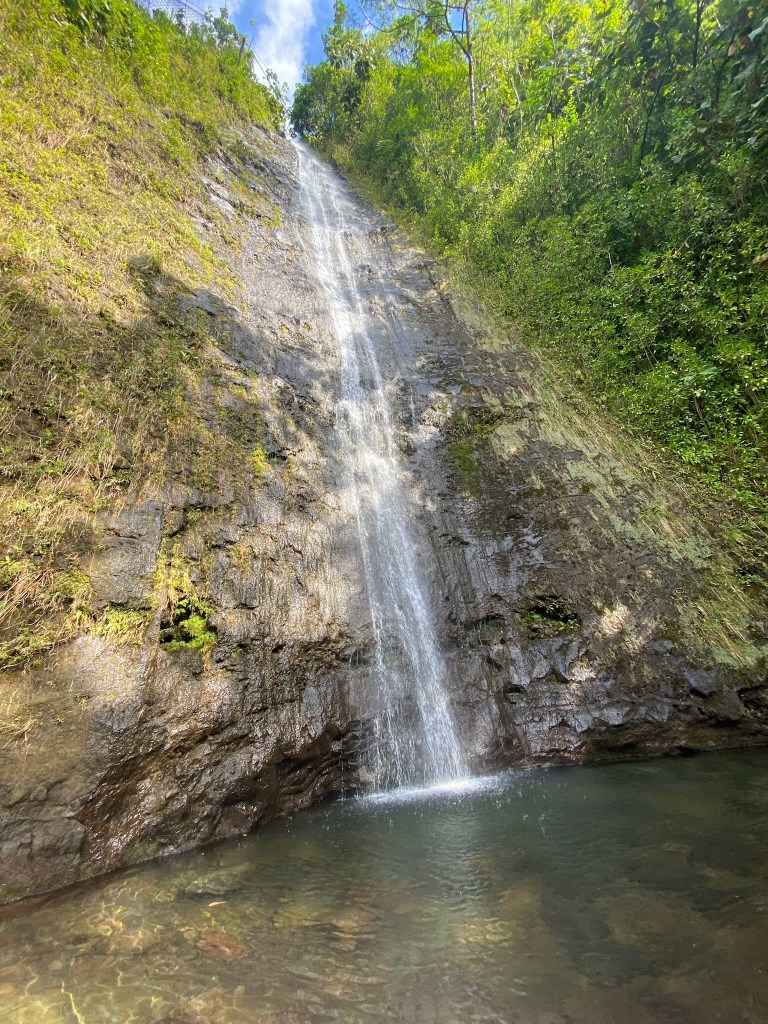 a large waterfall over some water in Manoa Oahu