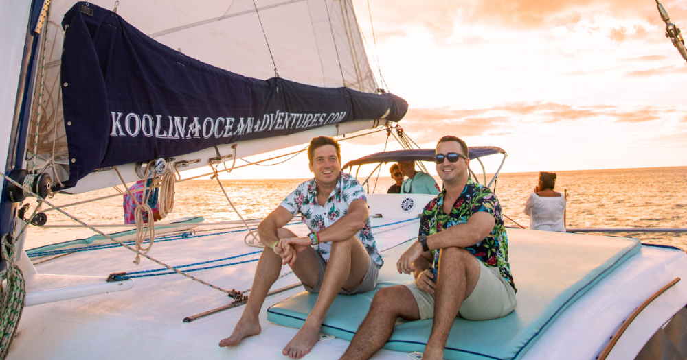 two friends sitting on a boat during sunset