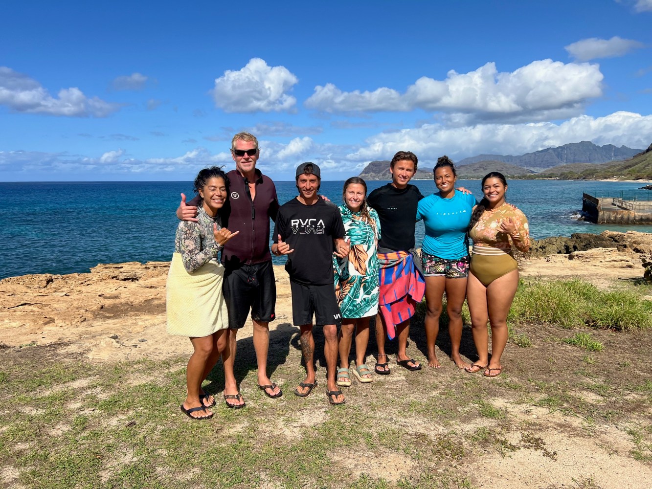 a group of people standing on a beach posing for the camera